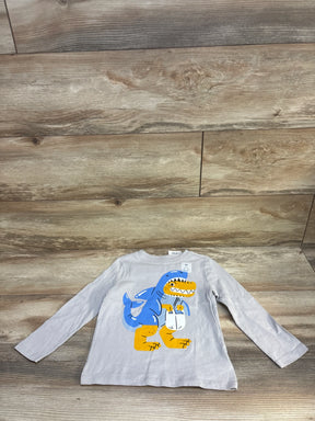 Kids grey long sleeve shirt with blue and yellow dinosaur graphic, laid on wood background