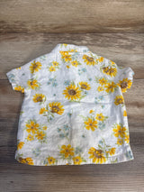White short sleeve toddler shirt with yellow sunflower print, back view on wood surface.
