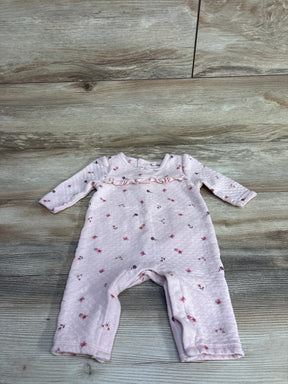 Pink quilted baby romper with long sleeves and small floral print on wooden floor