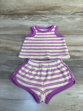 Top-down flat lay of newborn terry cloth tank top and shorts showcasing ivory with purple stripes and trim on wood background