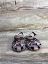 Front view of EYY mauve toddler sandals showcasing knotted bows, open-toe cutouts and ankle straps on light wood background