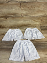 Three pairs of white kids' shorts with elastic waistbands on wood floor, ideal for baby and toddler clothing resale