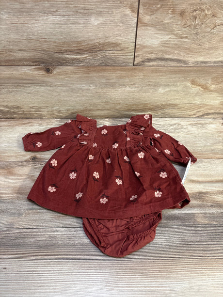 Flat lay of baby rust corduroy dress with matching bloomers, pink floral print and ruffled shoulders on light wood