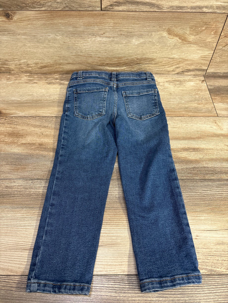 Children's blue denim jeans with back pockets on wooden floor background