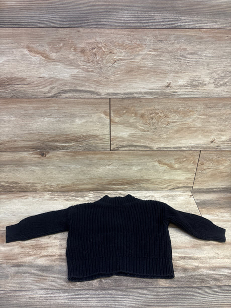 Front view of Baby Gap black knit button up cardigan in size 12 to 18 months showcasing ribbed texture on a wood look floor