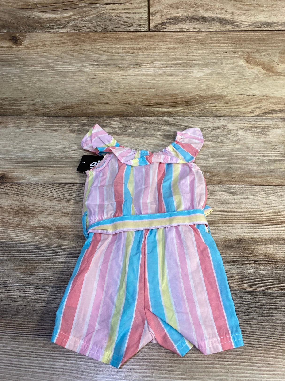 Top-down view of baby shortie romper, pink multicolor stripes, ruffle collar and elastic waist, size 3 months on wood floor