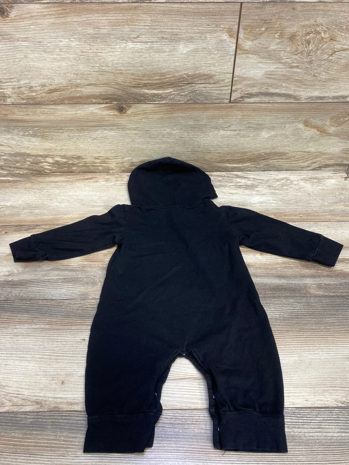Black hooded baby romper on wooden floor, soft and cozy for infants