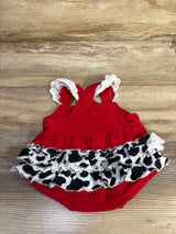 Top-down view of red Little Moo Moo bubble romper showcasing embroidered cow ruffles and lace straps on wood background