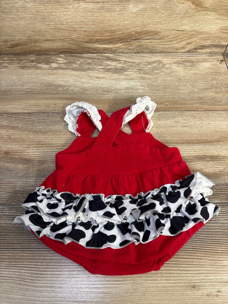Top-down view of red Little Moo Moo bubble romper showcasing embroidered cow ruffles and lace straps on wood background