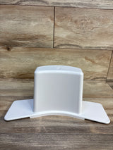 Front view of Super Potty Trainer adjustable back support showing white plastic curved base with side wings on wood floor background