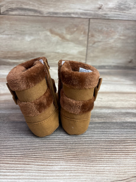 Rear view of brown faux-fur soft sole boots in size 4/5C with plush cuffs on a wood-look surface