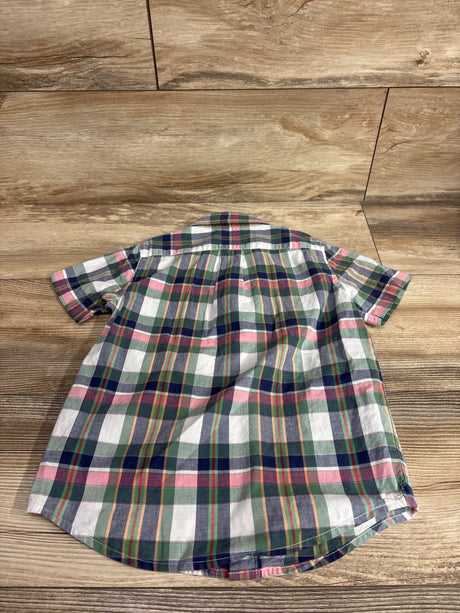 Back view of toddler poplin button-down shirt in green and pink plaid, short-sleeve with curved hem on wood background