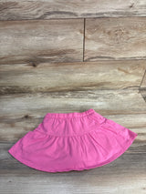 Flat-lay of girls' Jumping Beans pink skort showing elastic waistband and tiered skirt on wood background