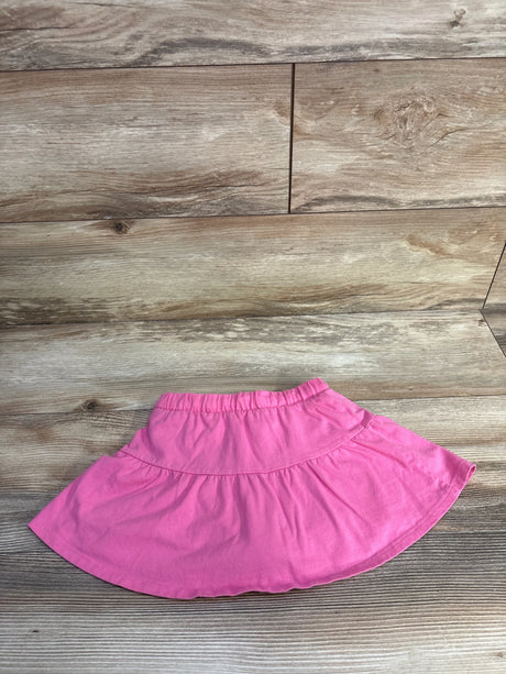 Flat-lay of girls' Jumping Beans pink skort showing elastic waistband and tiered skirt on wood background