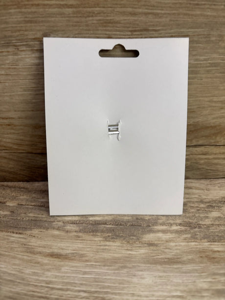 Back view of a white turkey applique hair bow on a display card with its metal clip visible against a wood-grain surface