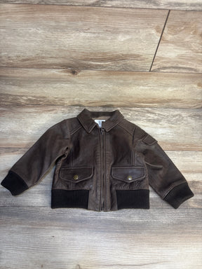Brown faux leather toddler jacket with front zipper and snap pockets on wood background