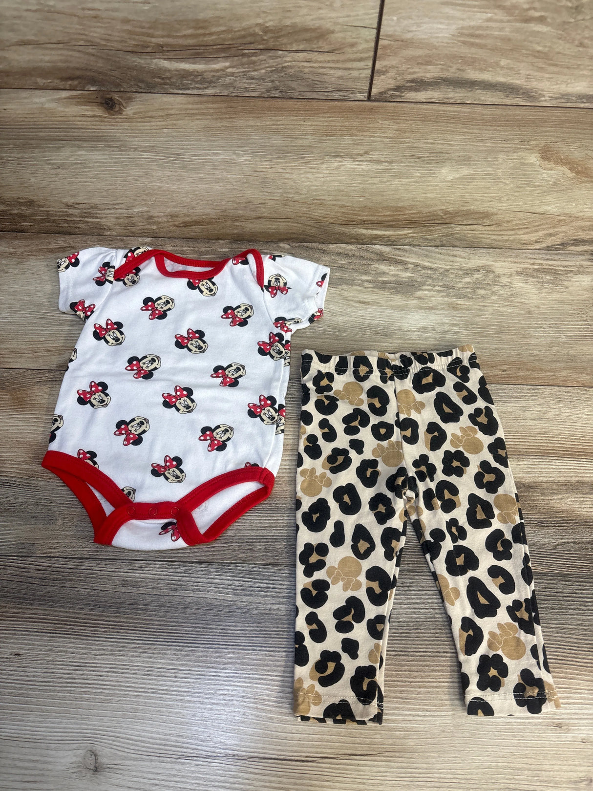 Baby outfit with Minnie Mouse print bodysuit and leopard print pants on wood floor