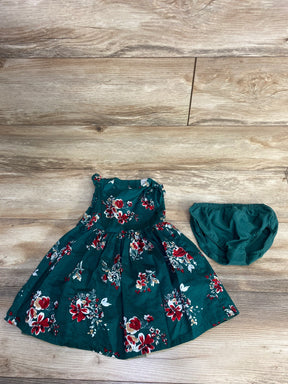 Green floral baby dress with matching diaper cover on wooden floor background