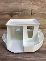 Front view of Dexbaby Spin Changing Station, white, showing rotating base with divided storage on wood backdrop