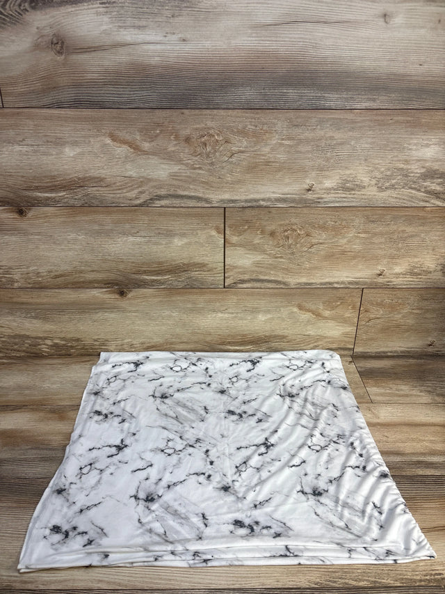 White marble-patterned baby blanket on wooden floor