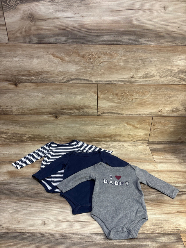 Front view of Hudson Baby 3-pack long-sleeve bodysuits in navy, striped, and gray, with I love Daddy text on wood background