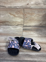 Three-quarter view of Nike Kawa toddler slide showing pink butterfly strap and elastic heel band on wood floor