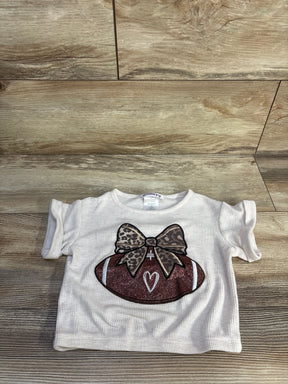 Flat-lay of beige waffle knit toddler football shirt (3T) showcasing glitter football with leopard bow on wood background