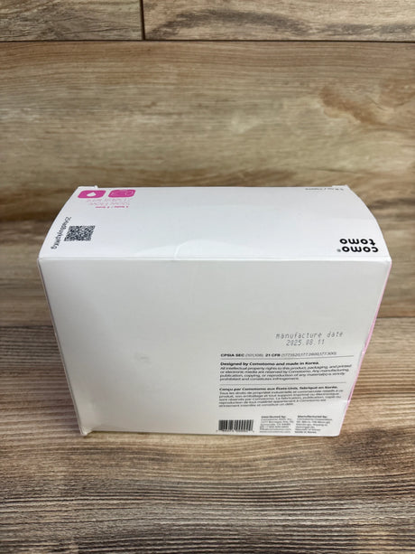 Top-back view of Comotomo 2-pack 5oz baby bottle box showcasing white packaging with pink accents on a wood surface