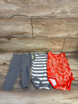 Flat lay of 3-piece baby tank bodysuit set showcasing grey leggings, a grey-and-white striped bodysuit, and a red crab-print bodysuit on wood background
