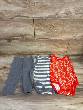 Flat lay of 3-piece baby tank bodysuit set showcasing grey leggings, a grey-and-white striped bodysuit, and a red crab-print bodysuit on wood background