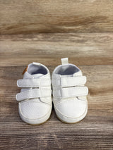 Front view of Myggpp First Walker baby sneakers showing dual velcro straps and pebbled white upper on wood background