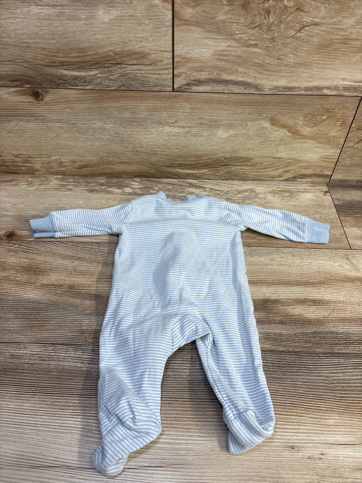 Top view of Carters blue ribbed sleeper in size 3 months showcasing long sleeves and attached feet with a wood-grain background
