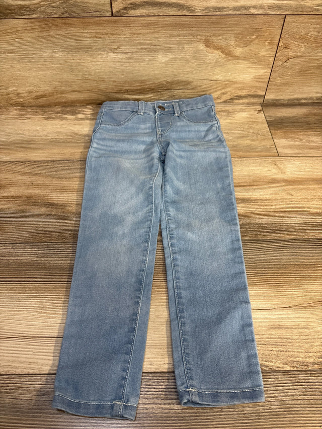 Light wash kids jeans laid flat on wood floor, perfect for casual wear and resale shopping.