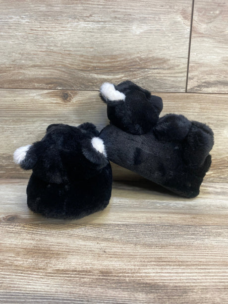 Black plush animal slippers for kids with white ears on wood background