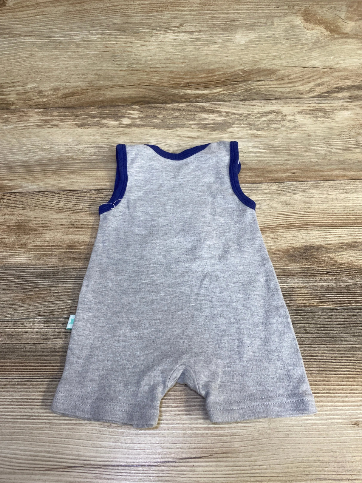 Back view of Millie and Myles Crab shortie romper showing navy trim and sleeveless grey fabric, laid flat on wood surface