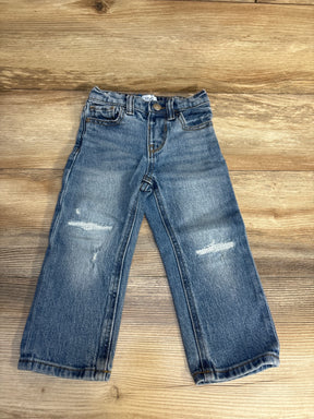 Kids distressed blue jeans with faded knees on wooden background