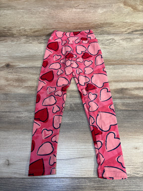 Pink children's leggings with red and pink heart pattern on a wood background