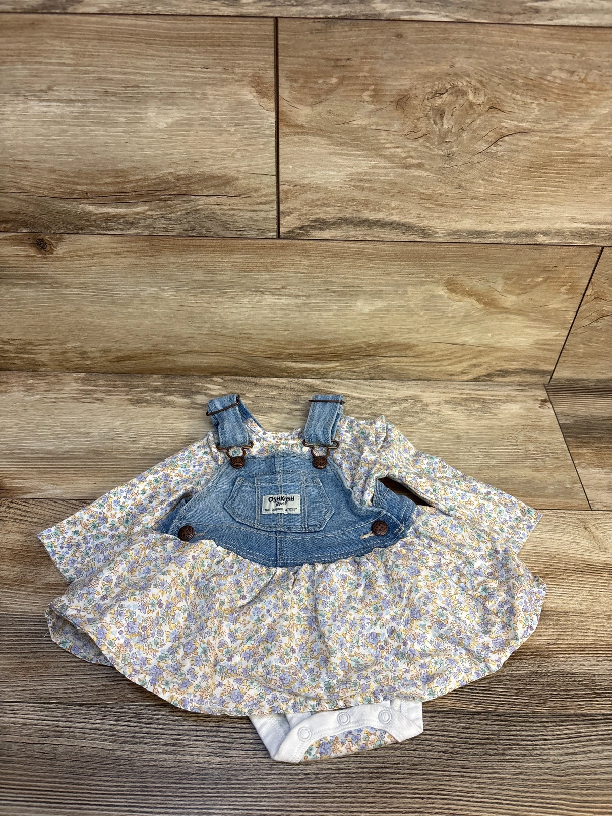 Floral baby romper dress with denim overall top on wood background