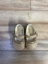Top view of Mayoral Mary Jane baby shoes in tan showing scalloped metallic trim, strap tassel, and polka-dot insole on light wood floor