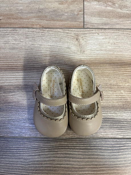 Top view of Mayoral Mary Jane baby shoes in tan showing scalloped metallic trim, strap tassel, and polka-dot insole on light wood floor