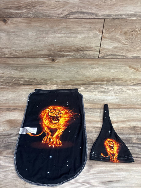 Front view of black 2-piece swaddle sack and hat set showcasing fire lion prints on a wood floor
