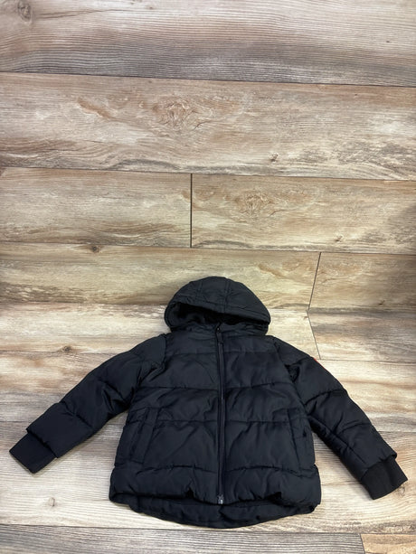 Front view of Okie Dokie puffer jacket in black, size 3T, showcasing hood, quilted panels, zipper, and pockets on a wood floor