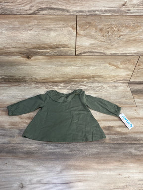 Olive green Carter's long sleeve baby shirt on wood background
