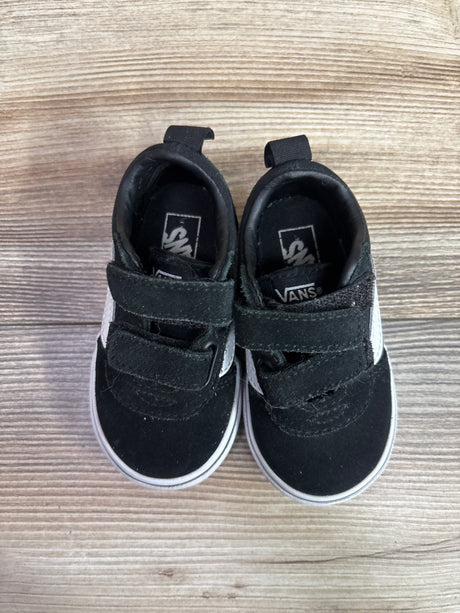 Top view of black Vans Old Skool V sneakers showcasing double hook-and-loop straps and white soles on a wood-grain background