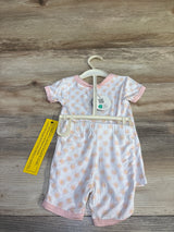 Back view of white bamboo baby pajama set with peach sunburst print and pink trim on hanger on wood floor