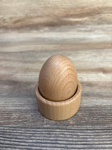 Front view of Lovevery Montessori Egg Cup showing smooth natural wood egg seated in a matching cup on a wooden tabletop