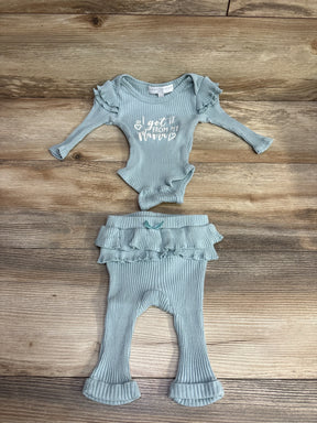 Light blue ribbed baby outfit with ruffle sleeves and text saying "I got it from my mama" laid on wooden surface