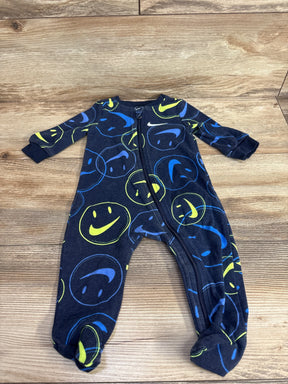 Navy blue baby footed sleeper with blue and yellow smiley face print on wood background