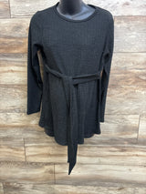 Front view of Ekouaer ribbed long-sleeve maternity top showcasing waist tie and textured fabric on wood-paneled background