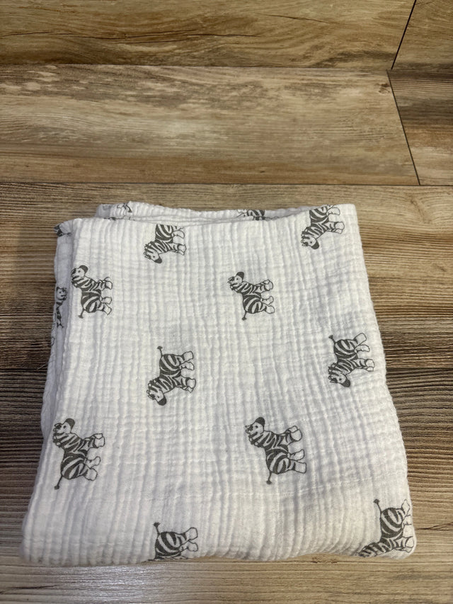 Top view of Amazing Baby muslin swaddle blanket in white with gray zebra print, laid flat on a wood floor